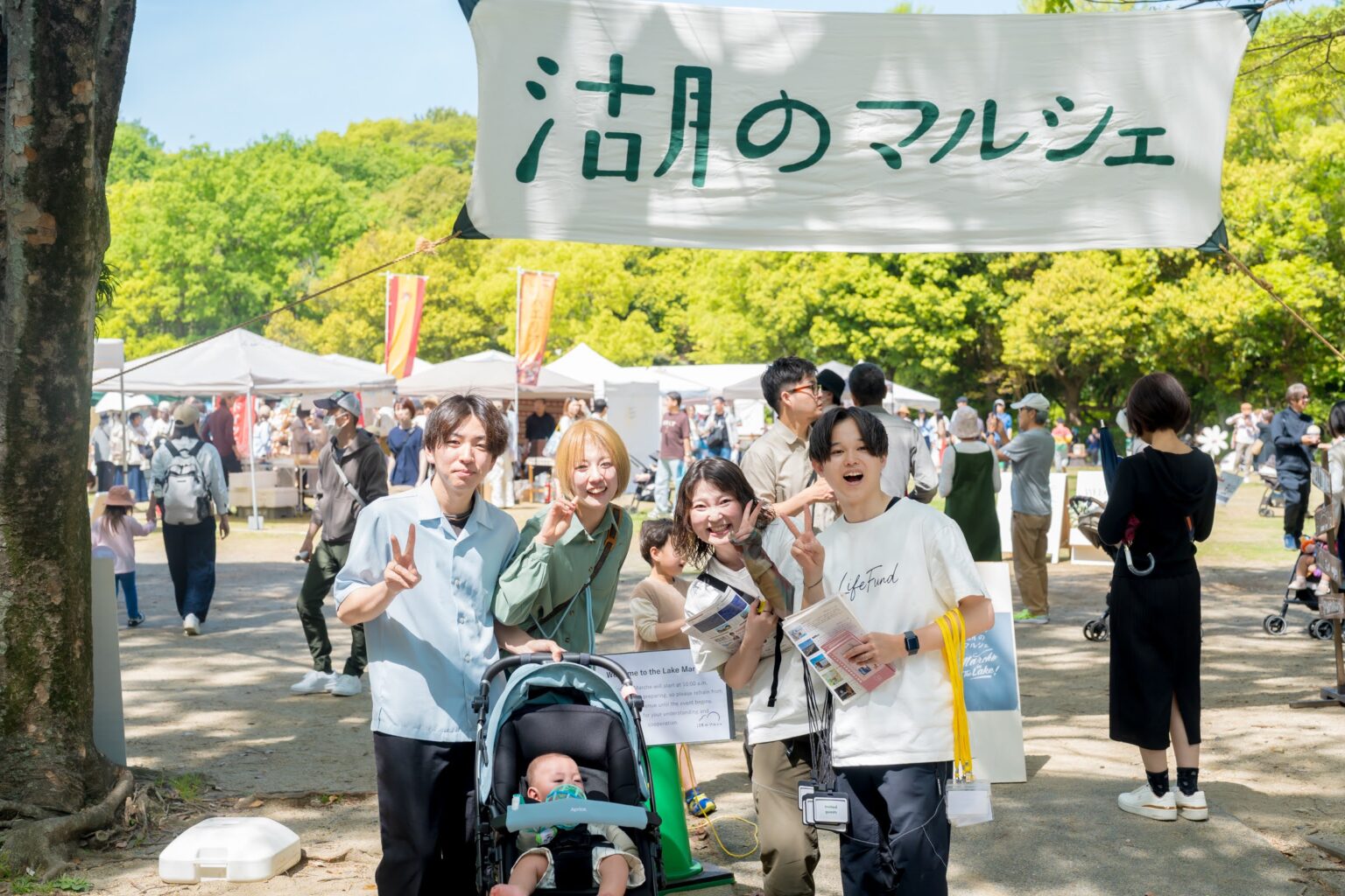 湖のマルシェの旗の下を歩く来場者