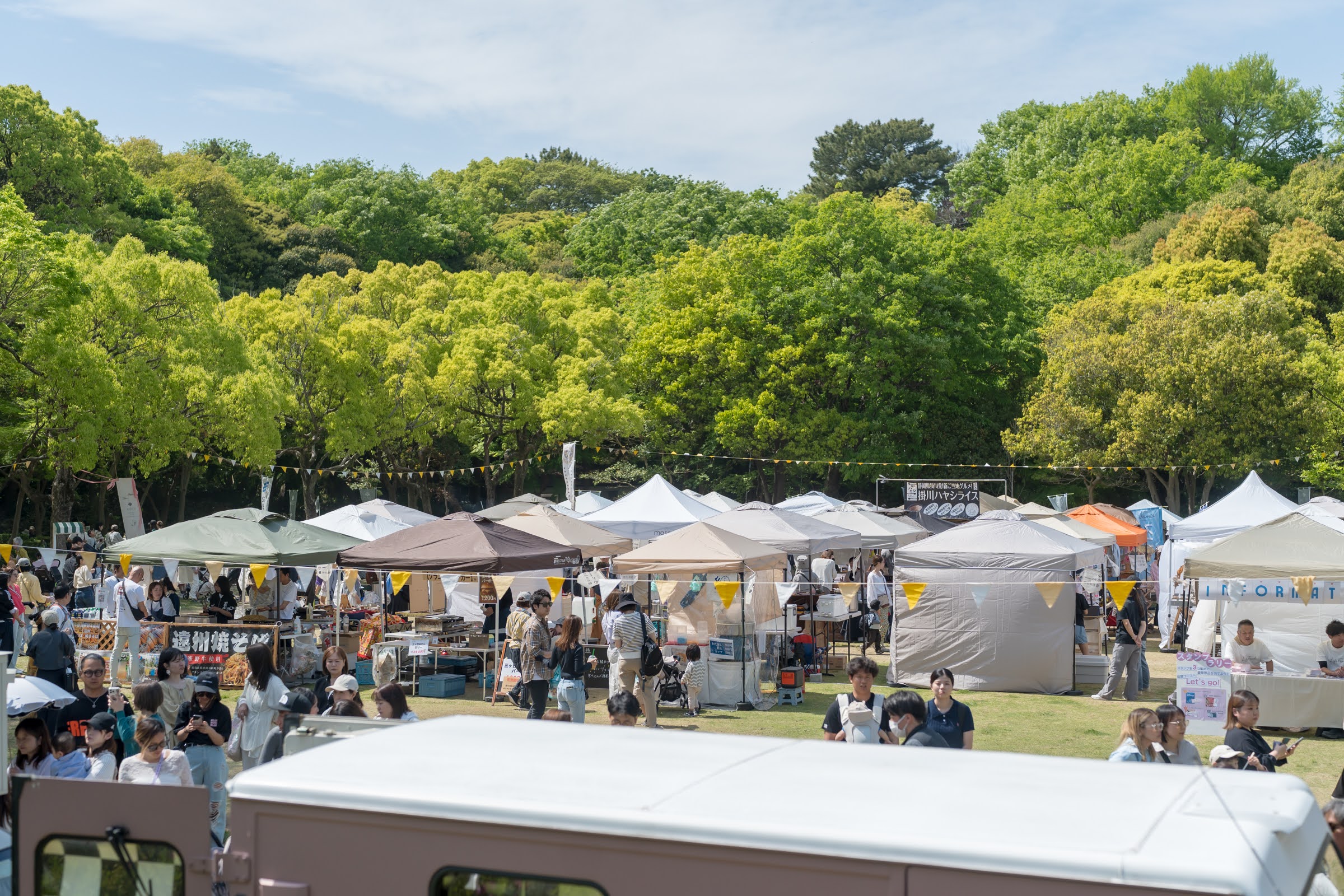 木々に囲まれた会場に並ぶテントと来場者